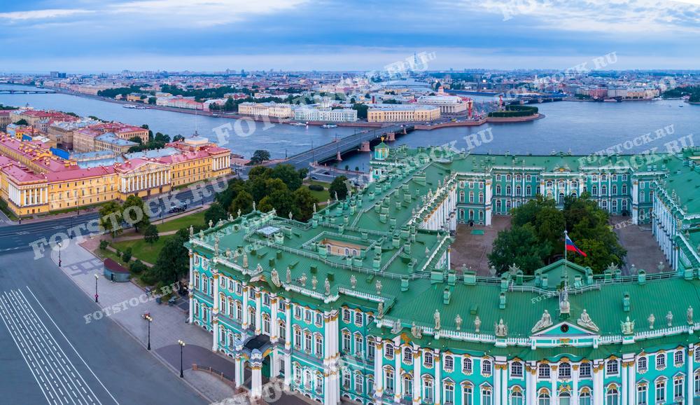 На фотографии представлен величественный вид на Зимний дворец и реку Неву в Санкт-Петербурге в ранние утренние часы, когда улицы ещё пусты. Этот снимок может быть использован для иллюстрации туристических гидов, исторических книг, образовательных материалов, а также в качестве фона для презентаций и веб-сайтов, связанных с культурным наследием города.